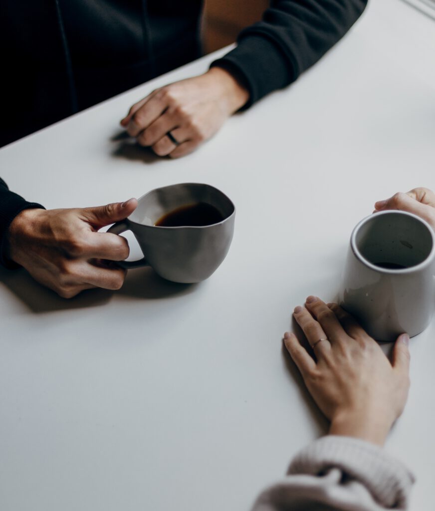 Zwei Personen mit Kaffeetasse am Tisch sitzend
